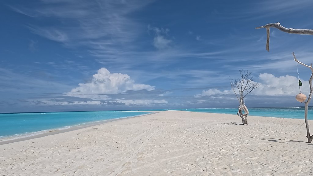 the sandbar at the end of Western tip of Fulhadhoo curves to the left and is fine white sand lapped by crystal clear turquoise water
